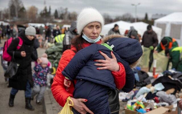 A woman carries her child as she arrives at the Medyka border crossing after fleeing from the Ukraine, in Poland on February 28. The head of the United Nations refugee agency says more than a half a million people had fled Ukraine since Russia’s invasion on Thursday.  - AP Photo
