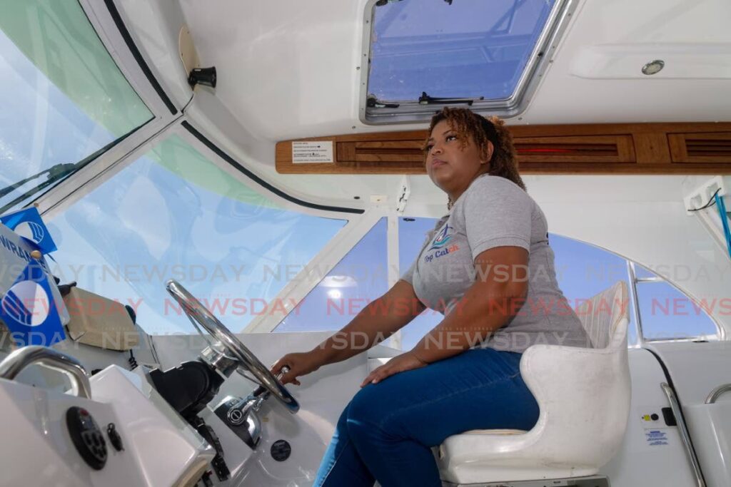 Shivonne Peters, managing director of Top Catch Charters, steers a tour boat in Tobago. - PHOTO BY DAVID REID