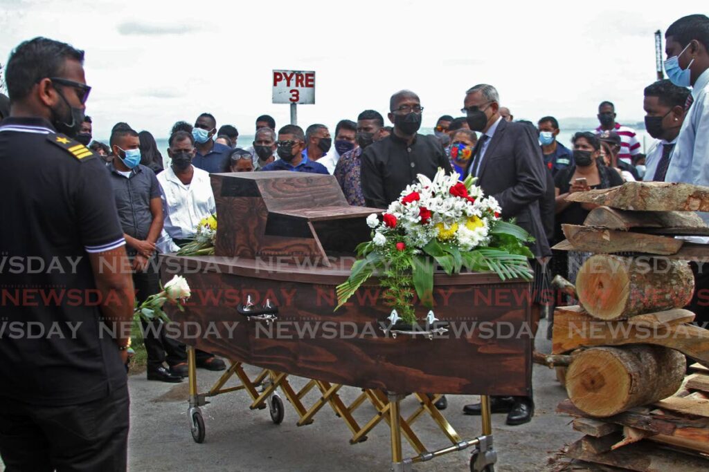 Mourners look on at the boat-shaped casket of Fyzal Kurban at his funeral at the Mosquito Creek Cremation Site, La Romaine, on Monday. - Photo by Marvin Hamilton