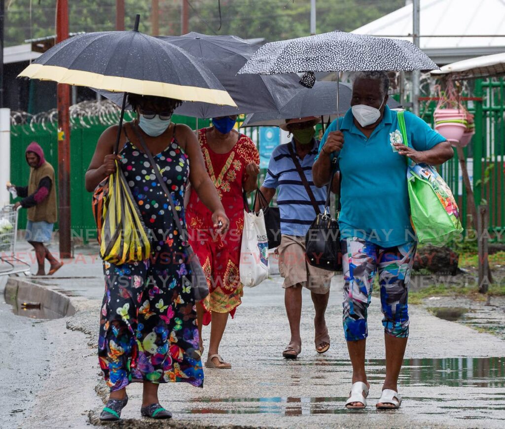 Shoppers leave the Scarborough market in Tobago with their produce while sheltering from the rain on March 5. The social economy plays an important role in the development of the Caribbean. - FILE PHOTO/DAVID REID