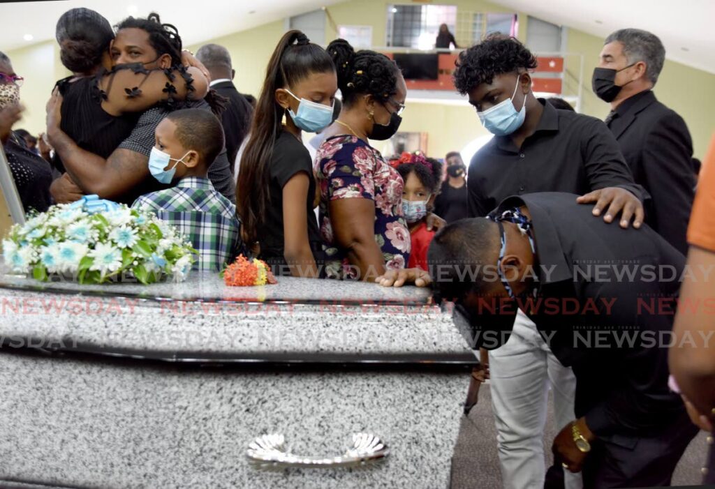 Christopher Boodram, lone survivor of the Paria accident, hugs the coffin of former colleague Yusuf Henry while beilng consoled by a friend at Henry's funeral at the Valencia Pentecostal Church on Kangalee Street, Valencia, on Wednesday. - AYANNA KINSALE
