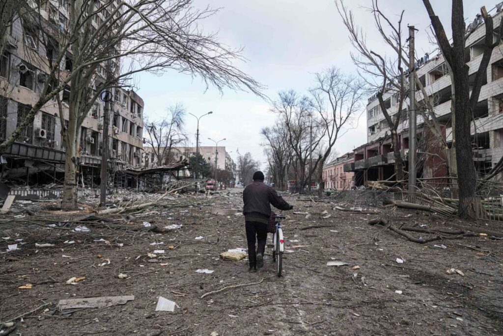 A man walks with a bicycle in a street damaged by shelling in Mariupol, Ukraine, on March 10. - AP PHOTO