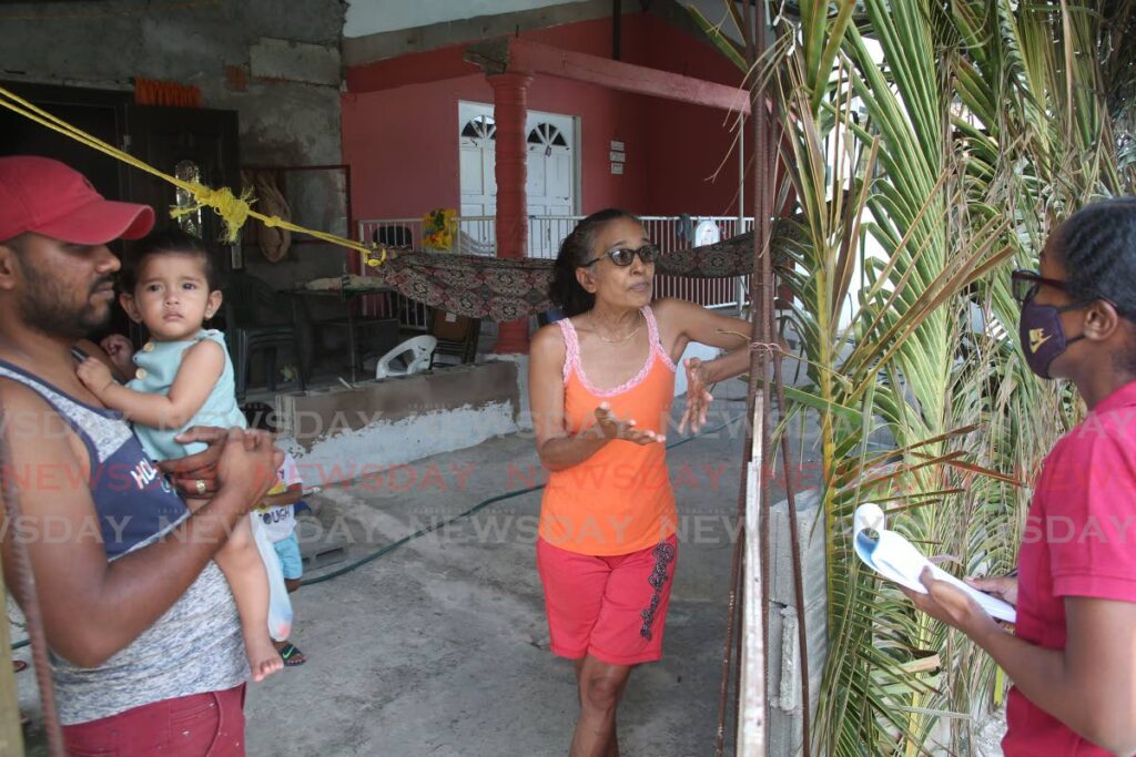 Marabella residents Riyad Sanichar, holding his daughter Mikayla, and Indra Sookram speaking with Newsday reporter Laurel V Williams on Saturday about NiQuan's plans to restart its plant in Pointe-a-Pierre.   - Lincoln Holder