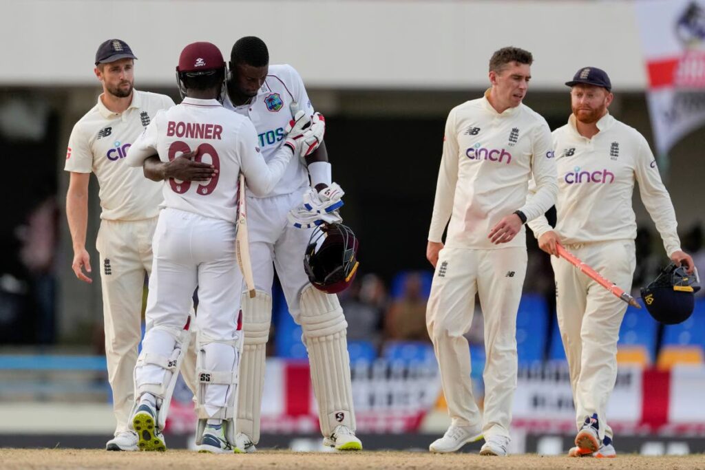Jason Holder (centre) and Nkrumah Bonner, of West Indies, embrace after day five of their first Test against England ended in a draw at the Sir Vivian Richards Cricket Ground in North Sound, Antigua on Saturday. (AP PHOTO) - 