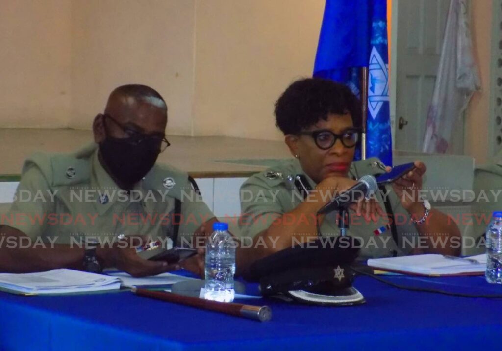 ACP Joanne Archie, right, holds her cellphone to the microphone for acting CoP McDonald Jacob to speak with Aranguez residents during a town hall meeting.  - Shane Superville