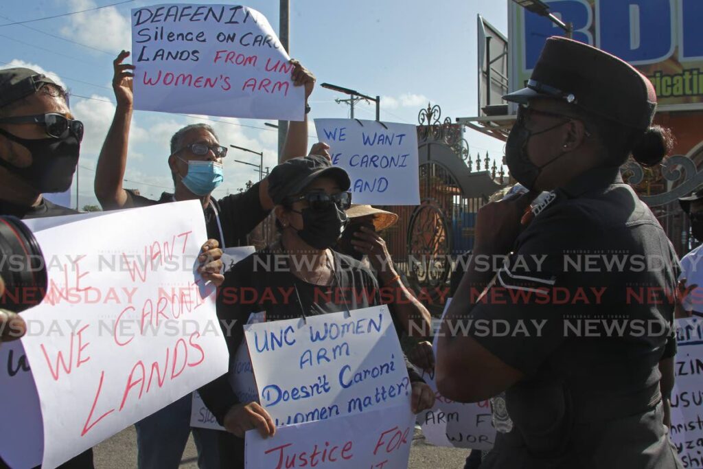 A police officer intervenes to bring peace between the ex-Caroni workers and the UNC supporters who squared off against each other in Chaguanas on Sunday. - Marvin Hamilton