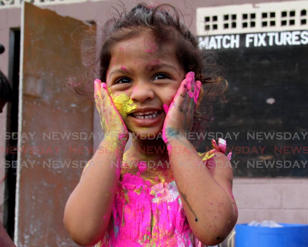 Rebecca Rampersad, two, smiles as she rubs abeer powder on her face during the El Dorado Village Council's Phagwa celebration at the El Dorado recreation ground. - AYANNA KINSALE