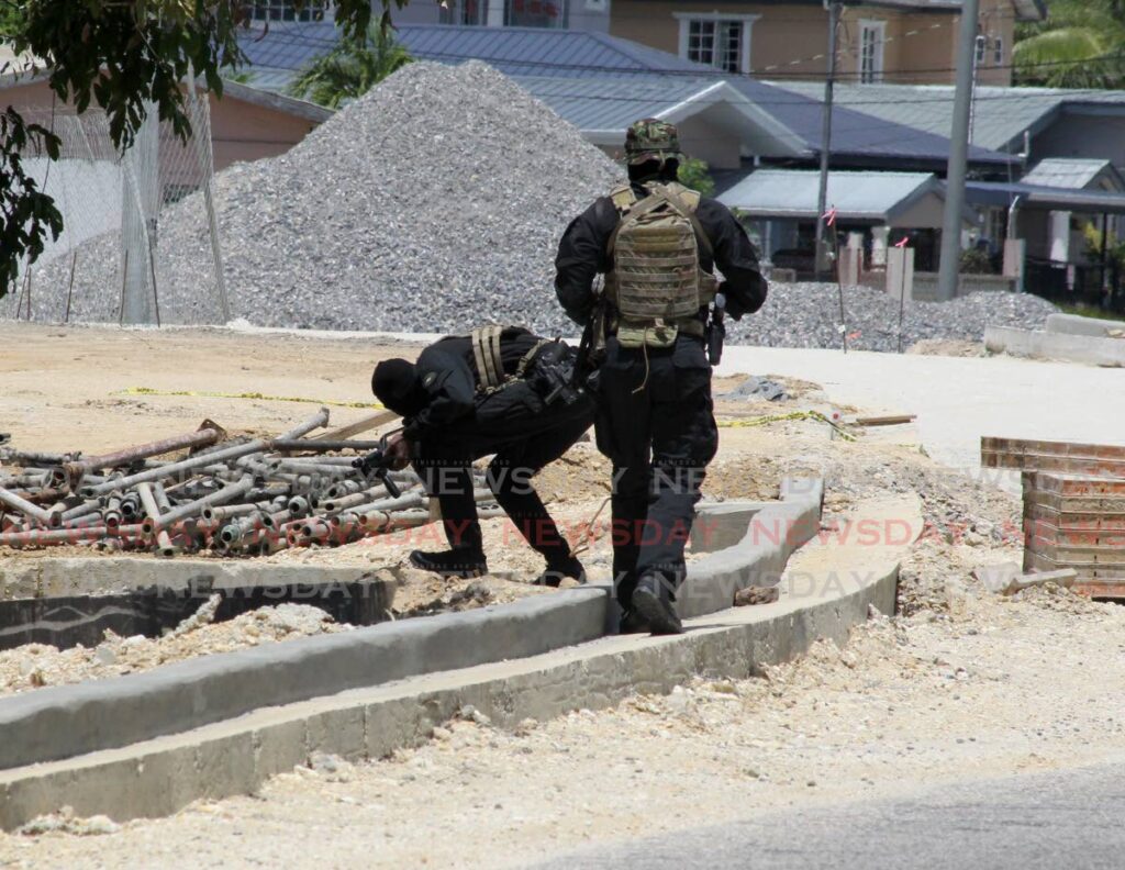 Members of the Elite Prisons Security Unit, make checks in drains on Trincity Central Road, Trincity, on Monday in an attempt to recapture the prisoners who escaped on Sunday night - ROGER JACOB