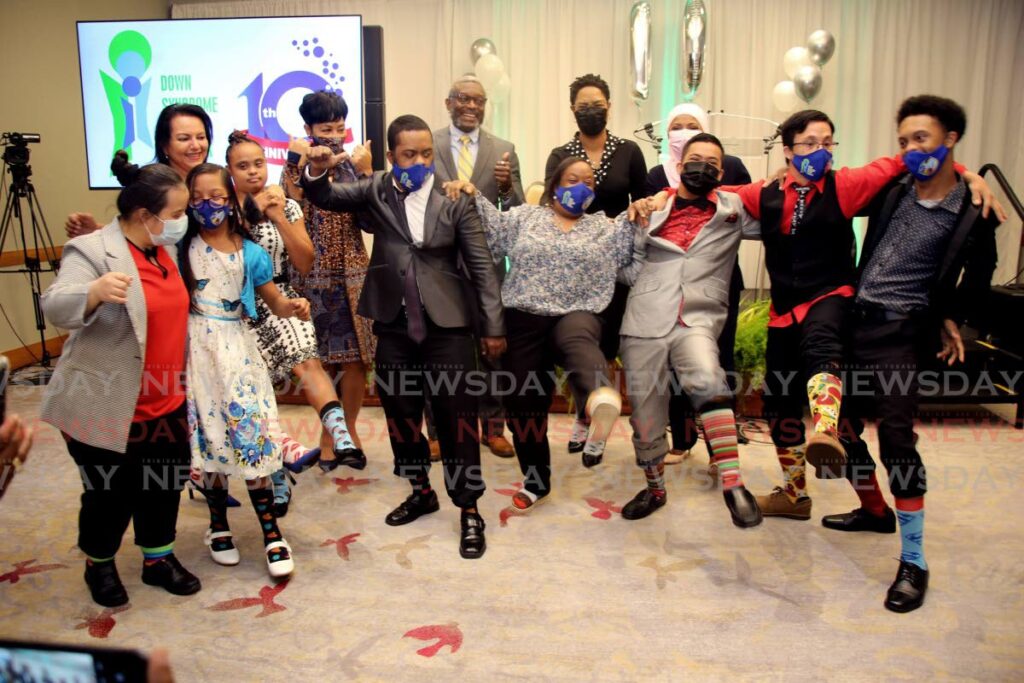 A group of youngsters show their colourful socks in celebration of World Down Syndrome Day at a Down Syndrome Family Network (DSFN) conference at the Hyatt Regency at the Waterfront in Port of Spain on Monday. With them at the back, from left, are Lisa Ghany, Sharon Rowley, DSFN founder Glen Niles and Minister Ayana Webster Roy. - SUREASH CHOLAI