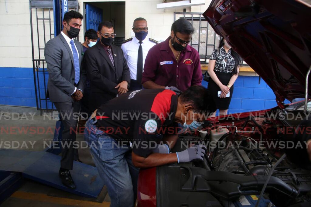 At the back, from left, Richie Sookhai, Works and Transport Minister Rohan Sinanan and Transport Commissioner Clive Clarke look as workers conduct an electronic vehicle inspection at Sookhai's Diesel Service inspection station on Charlieville. - SUREASH CHOLAI