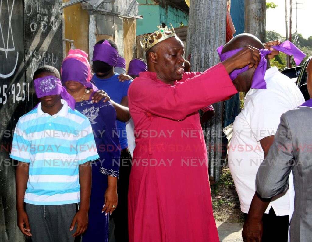 Spiritual Shouter Baptist Archbishop Dr Jerenmiah Mason, centre, blindfolds one the candidates to be ordained at the Holy Trinity Baptist Cathedral, St Joseph, on Sunday. - SUREASH CHOLAI