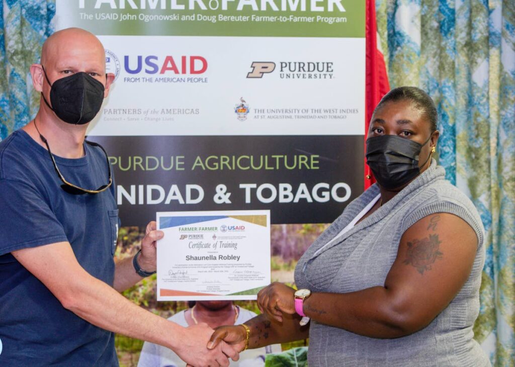 Thorsten Knappenberger, US-based volunteer, USAID John Ogonowski and Doug Bereuter Farmer-to-Farmer Program presents URP participant Shaunella Robley with a certificate of completion last Thursday. Photo courtesy THA