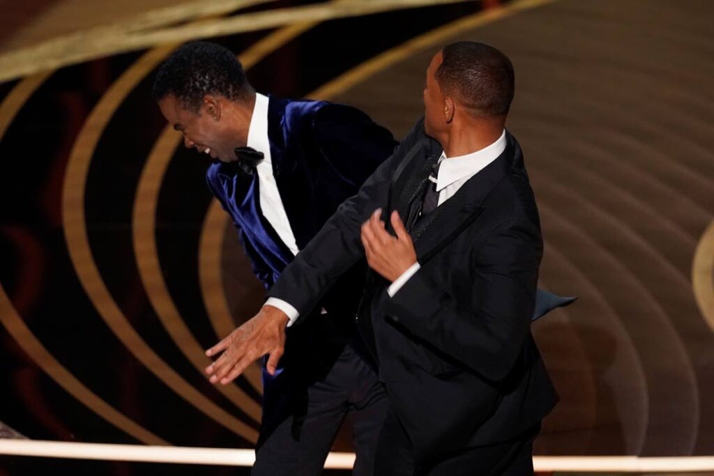 Will Smith, right, hits presenter Chris Rock on stage while presenting the award for best documentary feature at the Oscars on March 27 at the Dolby Theatre in Los Angeles. AP Photo - 
