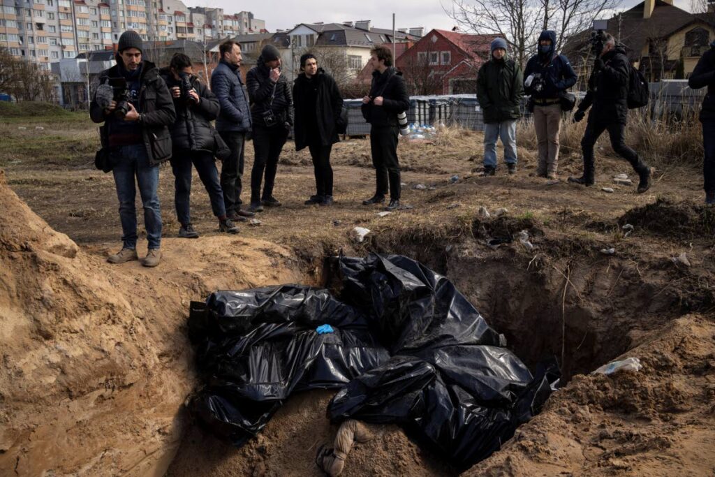 Journalists stand by a mass grave in Bucha, on the outskirts of Kyiv, Ukraine. (AP Photo)