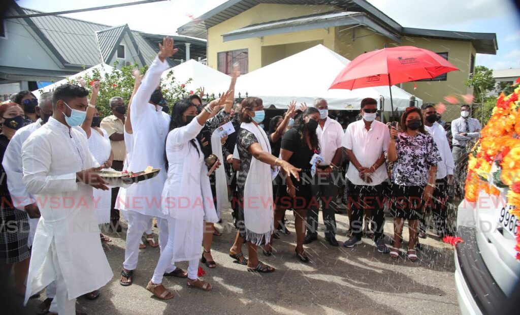 FAREWELL: Mourners throw rice at the hearse, as part of a farewell ritual, following the funeral for murdered mother of two Omatie Deobarran on Friday in Penal. PHOTO BY LINCOLN HOLDER - 