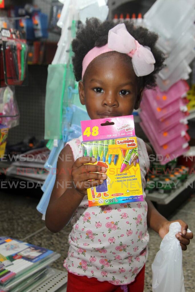 COLOURING ESSENTIALS: Kaynia Charles, three, with her box of crayons on Saturday at Naipaul's Book Store in Arima where parents gathered to engage in last-minute shopping for school supplies in time for the start of the new term on Tuesday. PHOTO BY ROGER JACOB - 