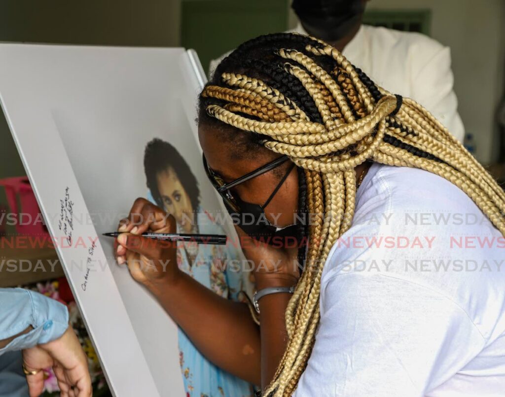 A mourner signs a portrait of Sharsa Alfonso-David. - PHOTO BY  JEFF K MAYERS