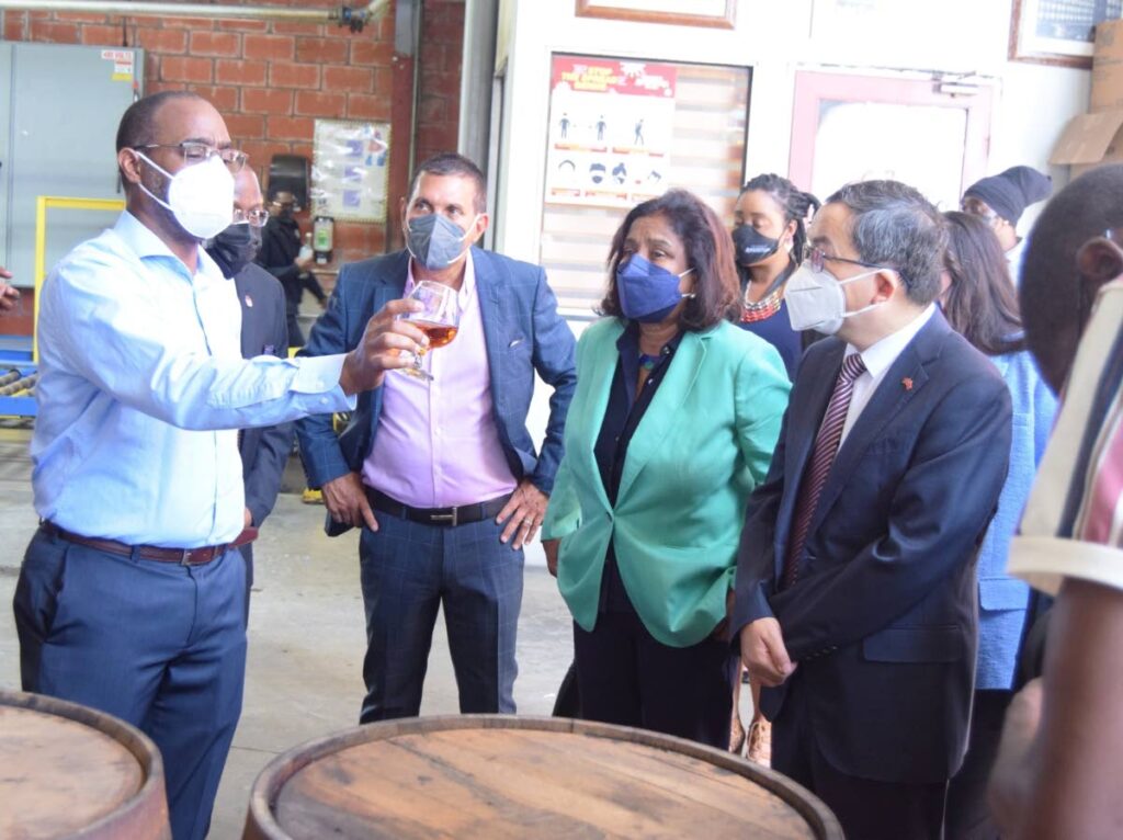 Trade and Industry Minister Paula Gopee-Scoon, Chinese Ambassador Fang Qiu and Angostura chairman Terrence Bharath listen attentively as master distiller John Georges showcases Angostura's 1919 rum while speaking on the process of rum aging during a tour  of the distillery in Laventille last Wednesday. - Photo courtesy Ministry of Trade and Industry