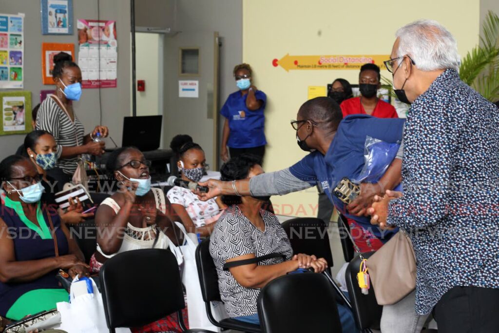 Health Minister Terrence Deyalsingh, assisted by a communications officer, takes questions from some of the women who turned up for health screenings at the Mt Hope Women's Hospital on Saturday. Photo by Roger Jacob