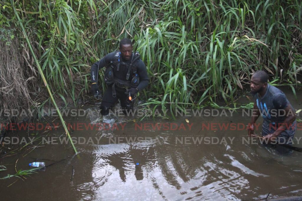 A diver and another man search a river near the missing child's Techier Village home. Photo by Marvin Hamilton