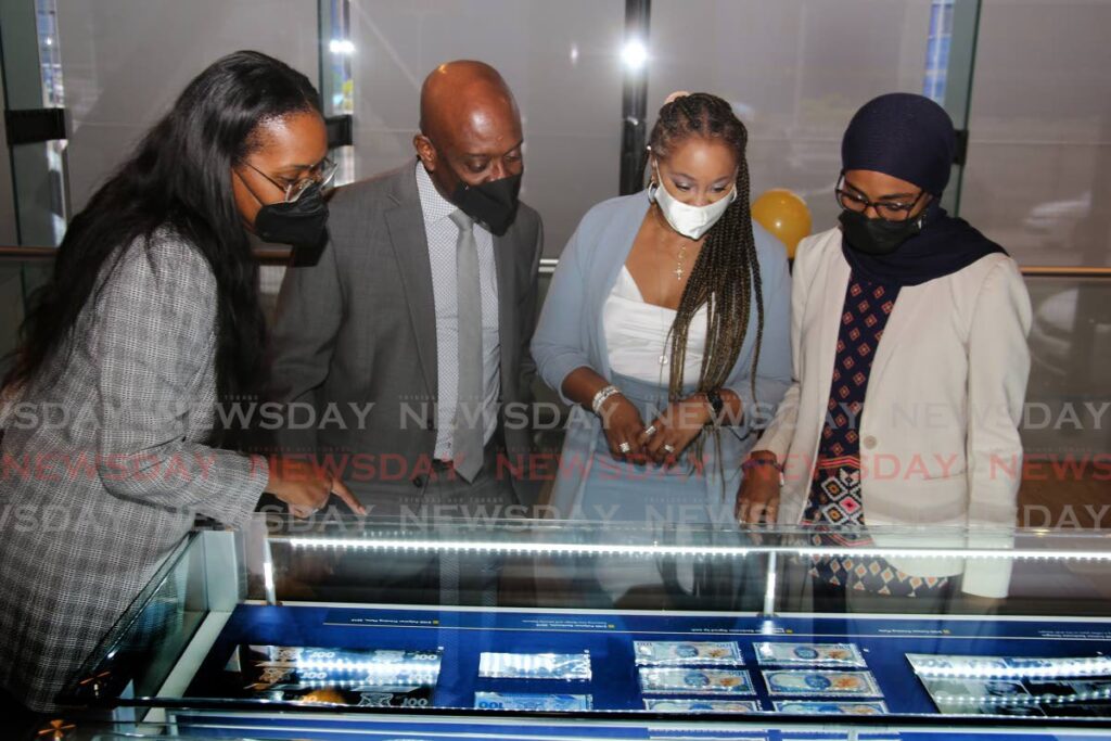 Central Bank Governor Dr Alvin Hilaire (second from left) looking at different $100 notes as the bank celebrates International Museum Day 2022 with the reopening of the Central Bank Museum at the Eric Williams Plaza on Independence Square in Port of Spain. With him, from left, are Central Bank staff members Christine Nanton Winter, Nicole Crooks and Nimah Muwakil. - Photo by Sureash Cholai 