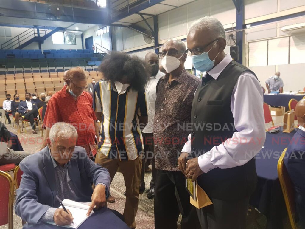 MP Rudy Indarsingh and trade unionist Sam Maharaj await their turn to have their copy of Adrian Cola Rienzi – The Life and Times of an Indo-Caribbean Progressive autographed by author Prof Brinsley Samaroo at Naparima College, on May 14. - YVONNE WEBB