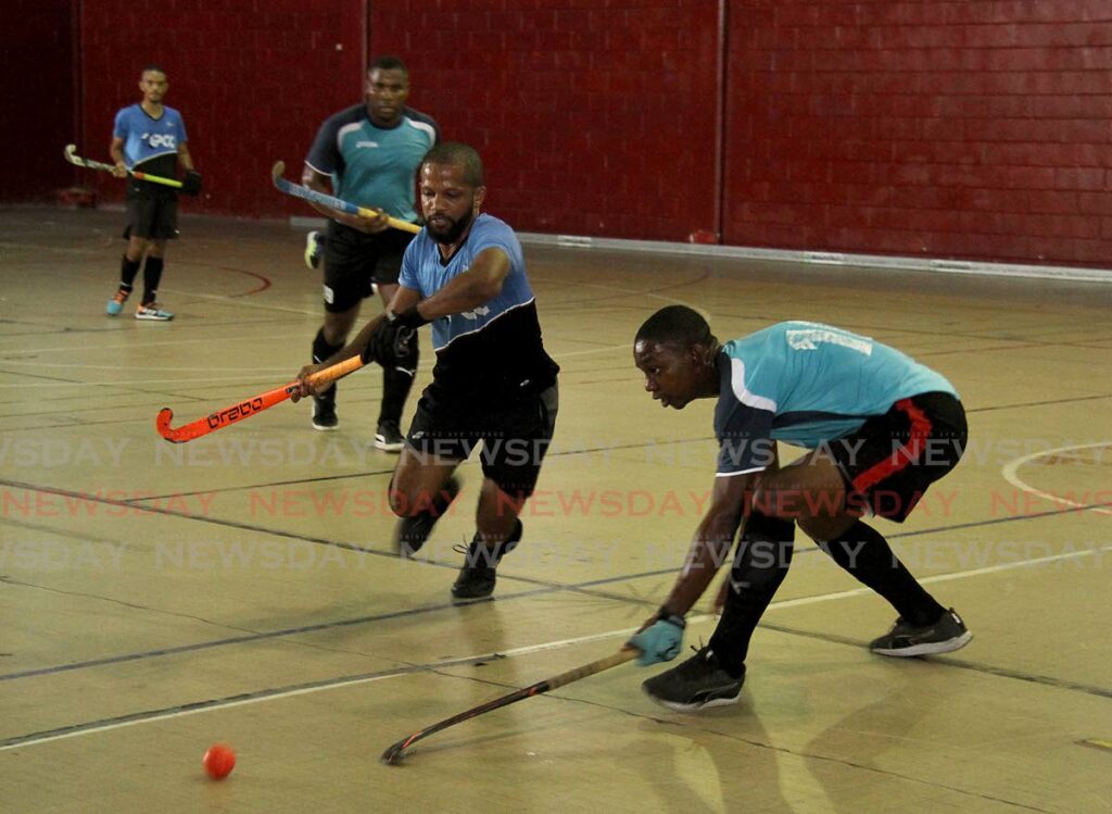 Queen's Park A player Darren Cowie (centre) and Sheldon De Lisle, of the Defence Force, battle for the ball during their teams' match in the TT Hockey Festival, at the Woodbrook Youth Facility, Woodbrook on Saturday. - AYANNA KINSALE