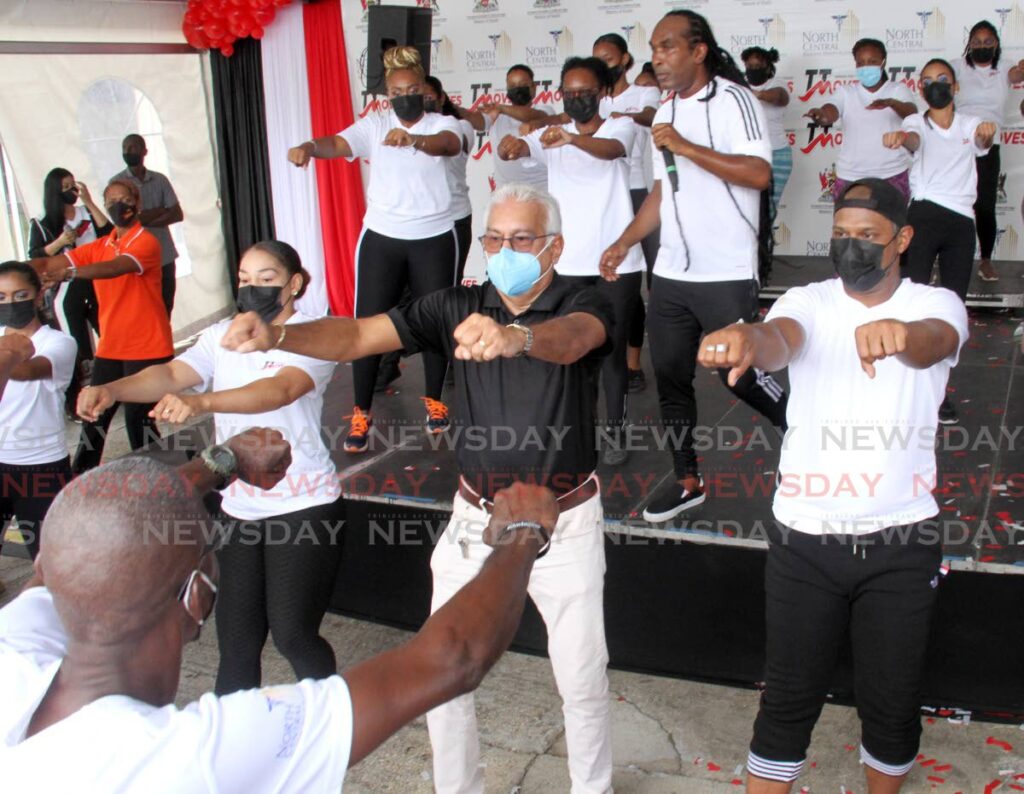 Minister of HealthTerrence Deyalsingh, centre, takes part in a “funrobics” session as Farmer Nappy performs at the launch of the TT Moves Building Signage Project at the Eric Williams Medical Sciences Complex, Mount Hope, on Sunday.  - AYANNA KINSALE