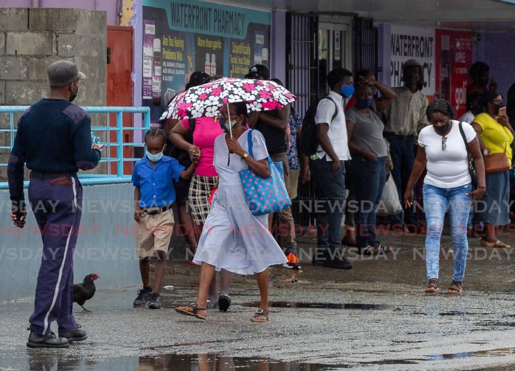 A woman uses an umbrella to shelter from the rain while others take cover near stores in Scarborough recently.  Photo by David Reid
