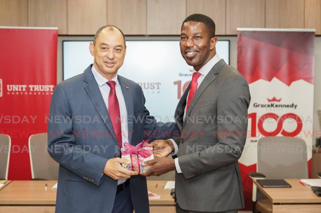 UTC executive director Nigel Edwards, right, and Don Wehby, Grace Kennedy Group CEO, exchange a gift to commemorate a joint venture agreement. Photo courtesy the Unit Trust Corporation. 