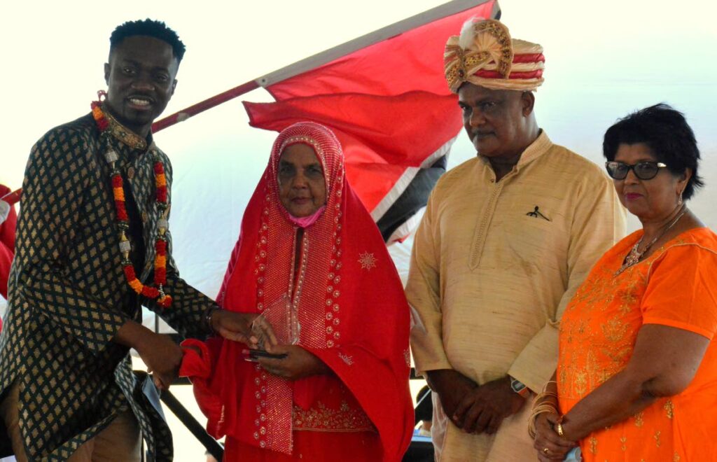 Chief Secretary Farley Augustine, left, presents Zaniffa Mohammed, second from left, and her son Azard with a token for their contribution to the development of Tobago at an Indian Arrival Day function on Sunday. Looking on is President of the Tobago Hindu Society Pulwaty Beepath. - 