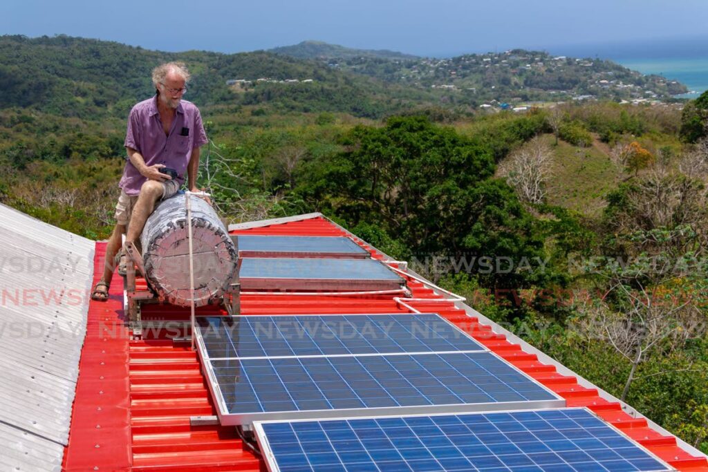 Ian Wright stands on his roof of solar panels at his home in Mason Hall, Tobago. - DAVID REID