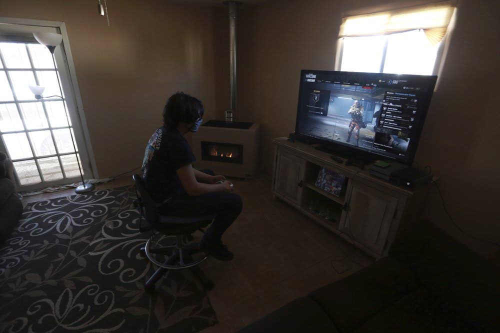 Javin Lujan Lopez, 17, a senior at Pojoaque High School, plays video games at his house in Española, New Mexico. (AP PHOTO)