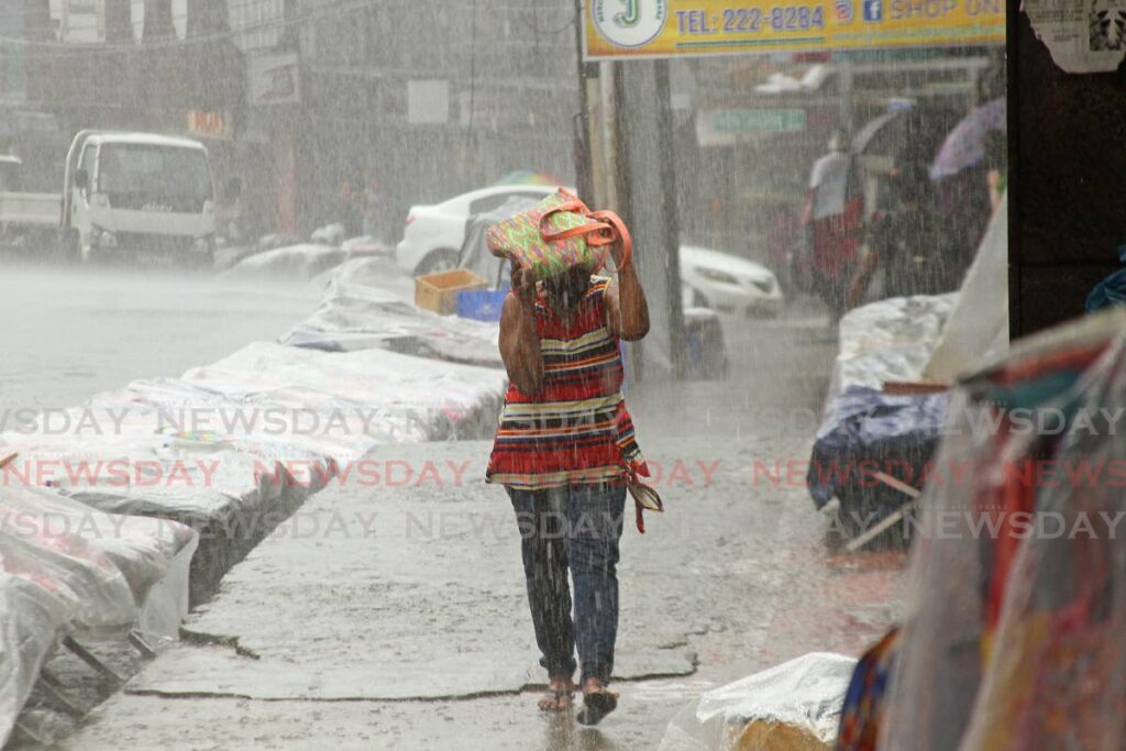 A woman braves a heavy shower in San Fernando. File photo - 