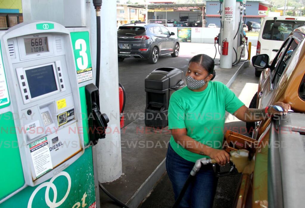 Attendant Denesyia Maharaj pumps gas for a customer at a Unipet gas station, San Fernando. - AYANNA KINSALE