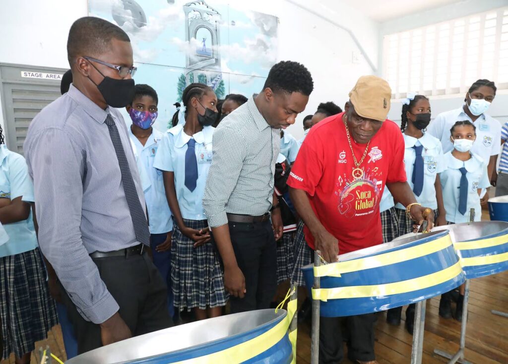 Speyside High Principal Alson Sylvester, left, and Chief Secretary Farley Augustine, centre, look on as Iran ‘Duce’ Anthony plays a note on one of the pans donated to the school last Friday.  - 
