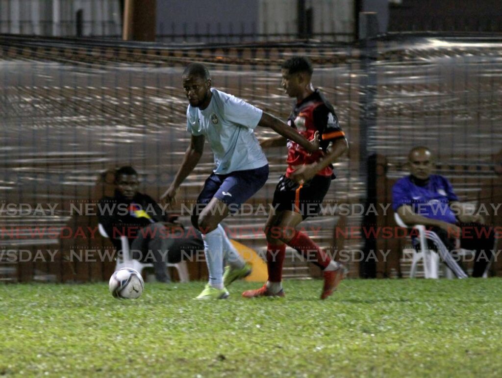 Police FC Clevon Mc Fee, left, and Central Soccer World Joel Bailey vie for control of the ball during the Ascension Football Tournament match, at the Police Barracks, St James, on Sunday. Photo by Ayanna Kinsale