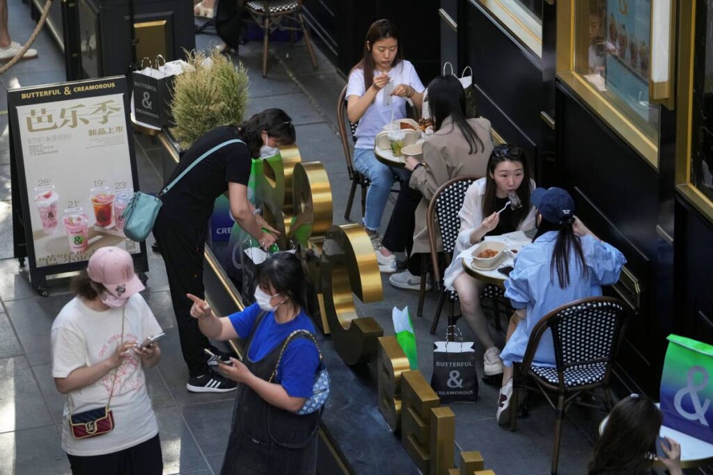Women wearing face masks chat with each other as people eat at a reopened restaurant in a shopping mall in Beijing on June 6. (AP PHOTO)