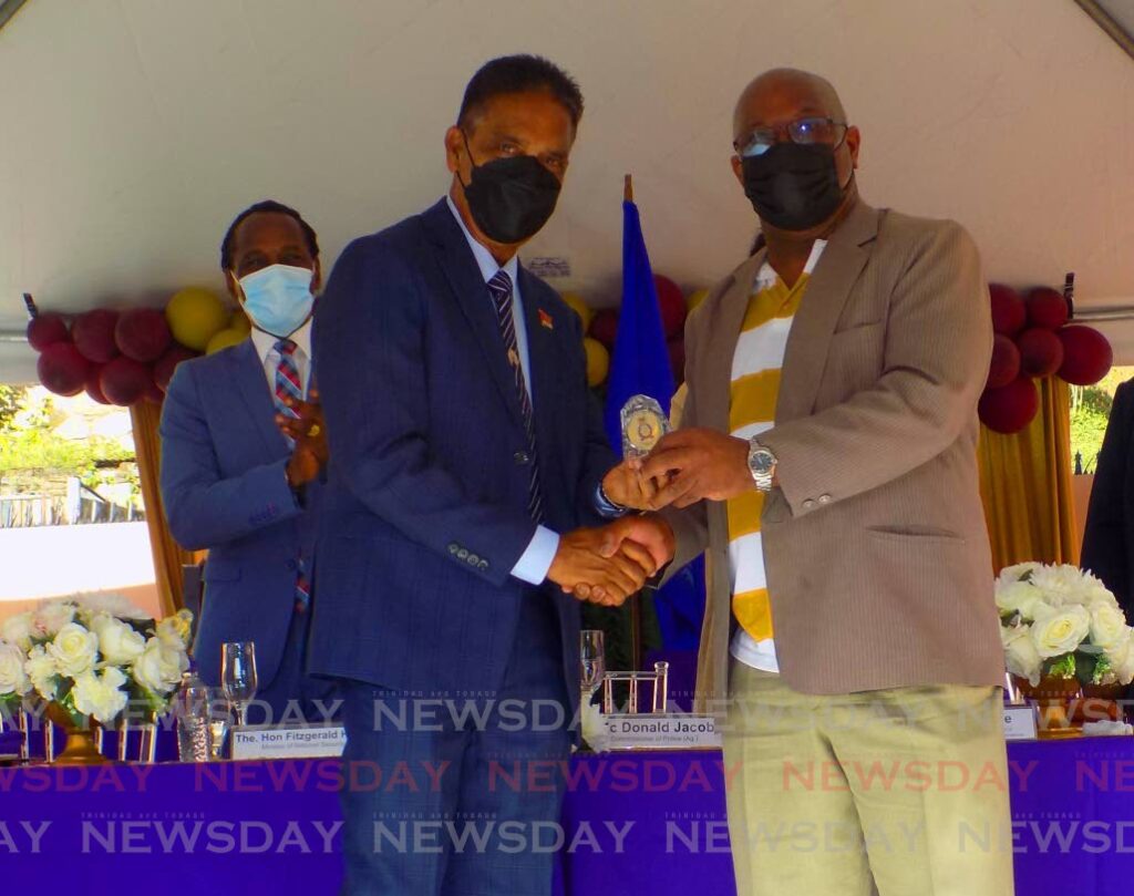 Retired Snr Supt of police Surendra Sagramsingh, left, receives an award from acting Police Commissioner McDonald Jacob during an awards ceremony for officers of the North Eastern Division in Santa Cruz on Sunday.  Photo by Shane Superville