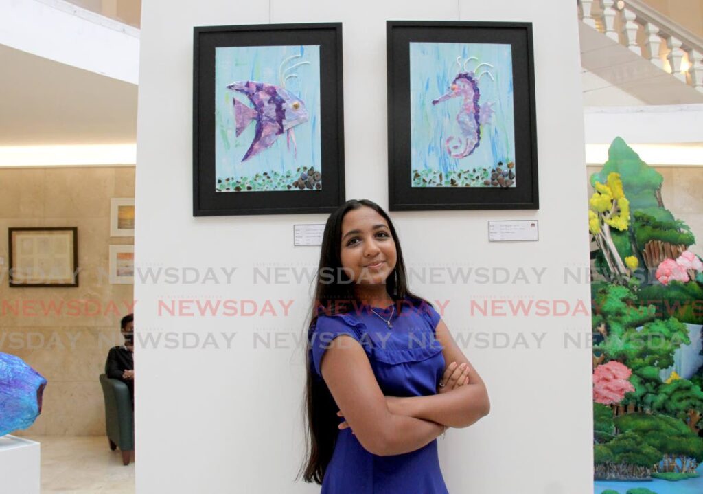 Jayda Ramjattan stands between her pieces unMASKing the Ocean-Angelfish, left, and unMASKing the Ocean-Seahorse at the  Rotunda Gallery, Red House, Abercromby Street, Port of Spain. - AYANNA KINSALE