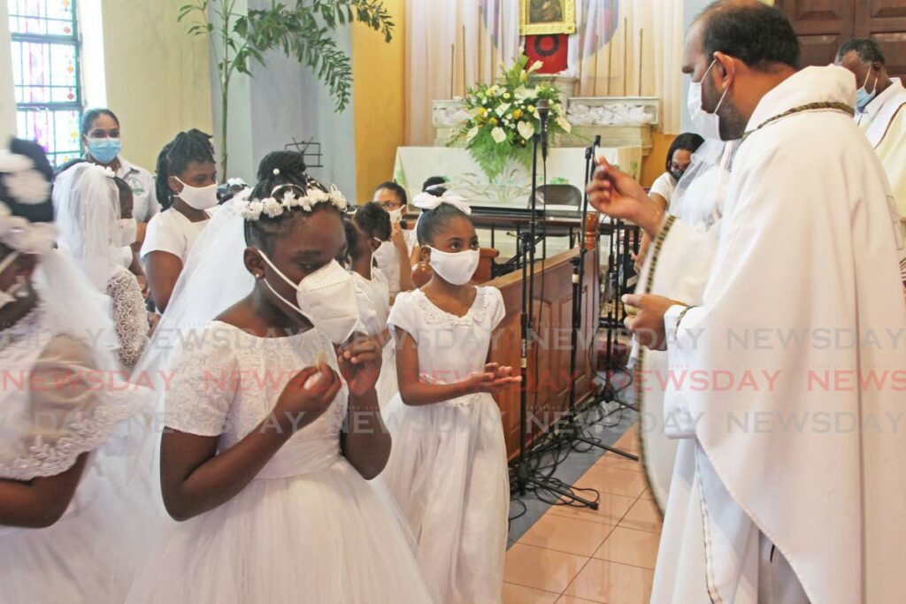 FIRST BODY: First communion students of Our Lady of Perpetual Help RC Church in San Fernando receive first communion on Corpus Christi on Thursday. - Photo by Lincoln Holder