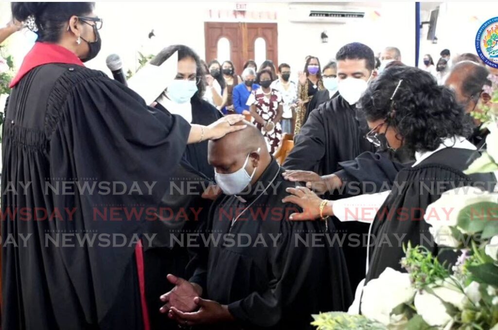 Presbyterian Moderator Rev Joy Abdul-Mohan and other ministers lay hands on Rev Robert Dinnoo after taking his vows at the ordination ceremony on Sunday at the Susamachar Presbyterian Church, San Fernando. - Yvonne Webb 