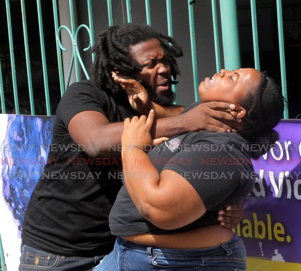 Derron Philanders pretends he is assaulting Kezzia Huggins in a D'Mad Company performance at the Tunapuna market Saturday as part of a campaign about gender- based violence.  - ANGELO MARCELLE