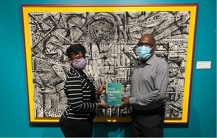 Andrew Jacque presents a complementary hard-cover copy of the book to a representative at  the National Library and Information System Authority (Nalis) Heritage Library Division. - 