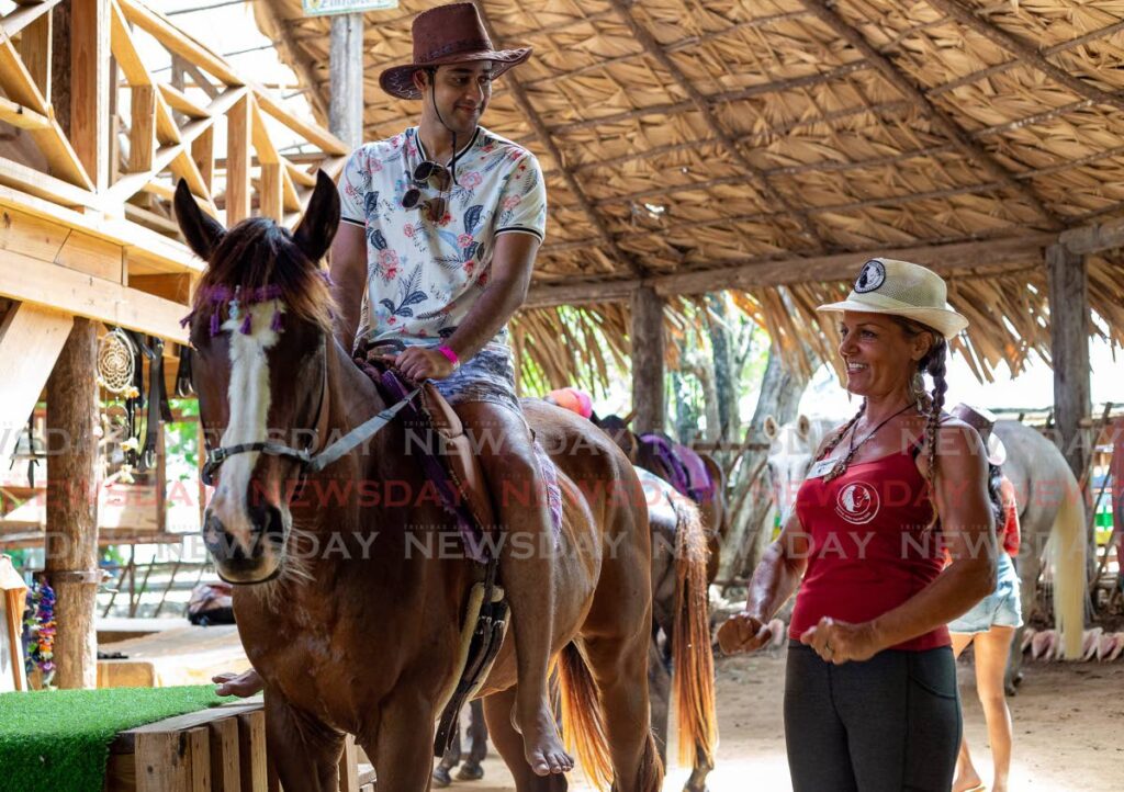 Veronika Danzer LaFortune, co-founder of Healing with Horses, shows a Trini client the correct posture when sitting on a horse at the Healing with Horses park, Buccoo.  Photo by David Reid