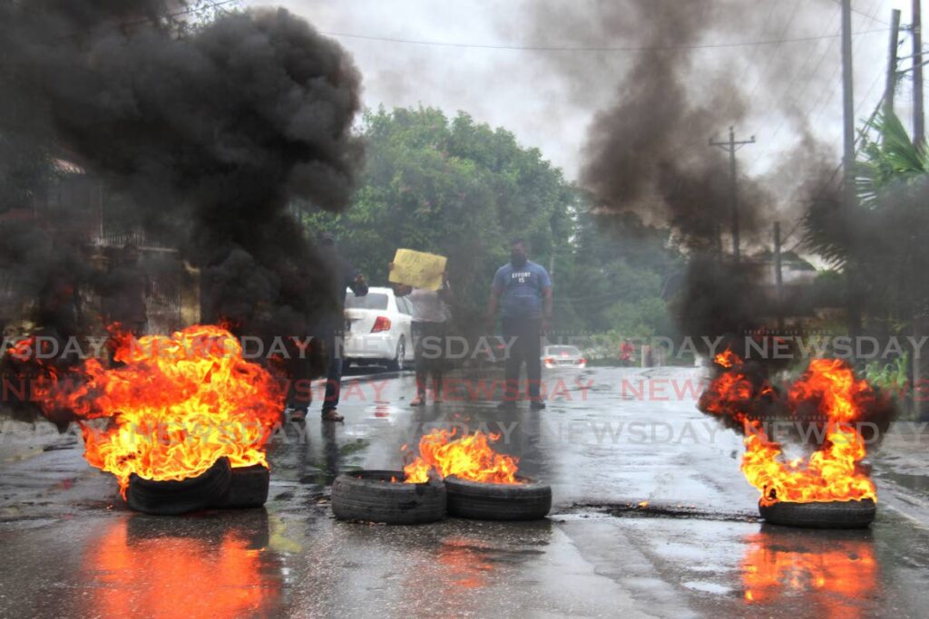 FIERY PROTEST: Tyres burn along this road in Avocat, South Oropouche on Tuesday as residents and their councillor protested damage done to the road by WASA workers who undertook underground pipe replacement. PHOTO BY MARVIN HAMILTON