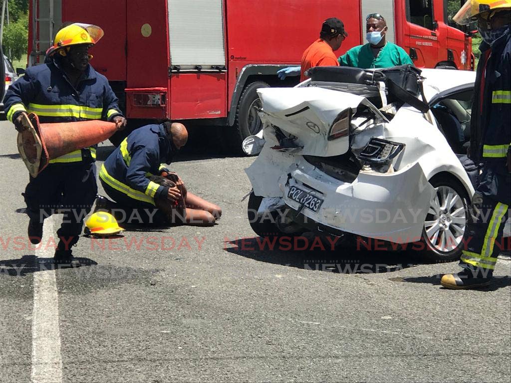 A fire officer attends to a teenager who was injured during a two-car accident along the Claude Noel Highway, Lowlands on Sunday.  - David Reid 