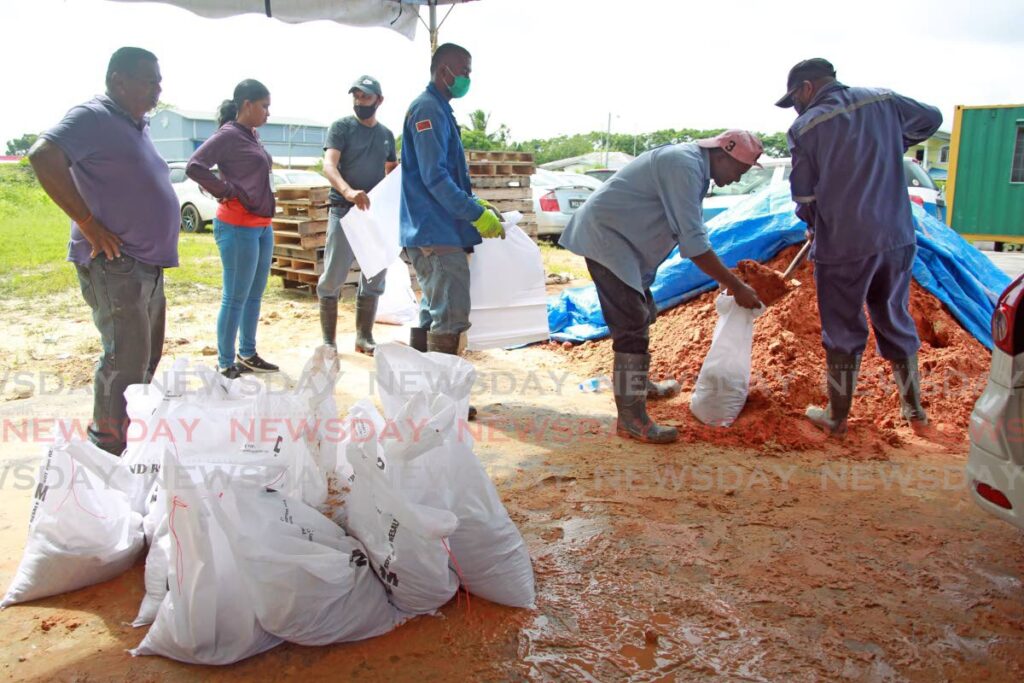Workers from the Penal/Debe regional corporation assist a resident who came to collect sandbags as they  prepare for major rainfall over the next 48 hours during the passage of a tropical wave. - Lincoln Holder