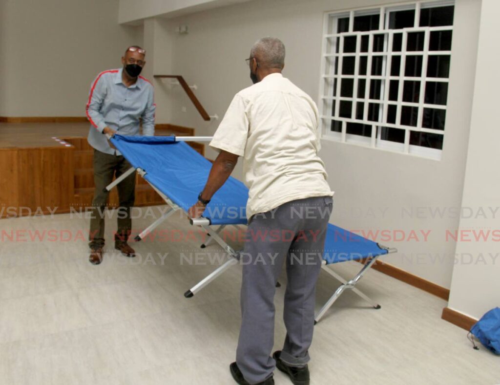President of the Belmont Community Centre Brian Cooper, left, assists a St Ann's resident in preparing a cot at the Belmont Community Centre, Jerningham Avenue, Belmont, on Tuesday evening. The resident was the first to be admitted to the disaster shelter housed at the community centre ahead of a storm that hit Trinidad and Tobago on Tuesday. Photo by Ayanna Kinsale