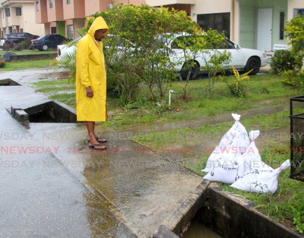 A Greenvale resident looks on as water levels in the drain start to rise quickly on Tuesday. Photo by Angelo Marcelle
